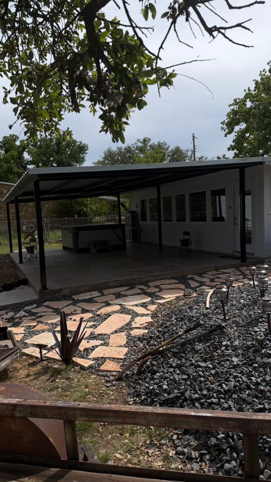 Covered patio with black metal frame and concrete slab