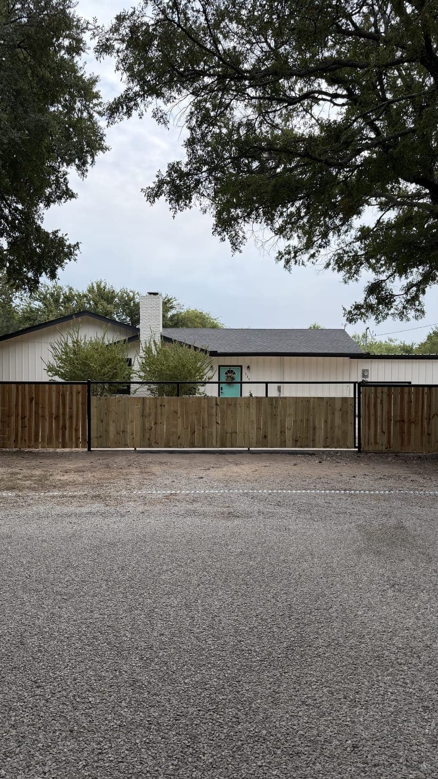 Wood privacy fence on a black steel frame running across the front of a white house